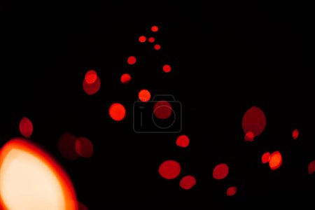 Foto de Rojo, purpurina y bokeh en un estudio con fondo oscuro para la celebración, evento o fiesta. Confetti, luces y destellos de color para la magia, brillo o resplandor para festivo por fondo negro con maqueta - Imagen libre de derechos