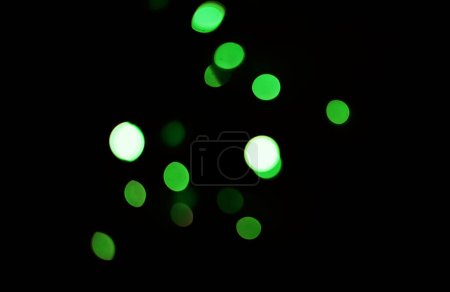 Foto de Luz verde, bokeh y puntos sobre fondo oscuro aislados en un espacio de maqueta. Desenfoque, fondo negro y brillo desenfocado, brillo o purpurina en la noche para Navidad, vacaciones o fiesta con magia de color. - Imagen libre de derechos