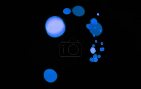 Foto de Bokeh, partículas azules y luces sobre fondo oscuro con patrón, textura y maqueta con estética cósmica. Iluminación nocturna, puntos brillantes y brillo en el fondo de pantalla negro con espacio, brillo de color y destello - Imagen libre de derechos