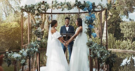 Photo for Women, lesbian wedding and ceremony outdoor with priest for love, celebration or together for commitment. Gay marriage, event and party with bride, black man or vows in nature, lgbtq couple or garden. - Royalty Free Image