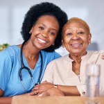 Portrait, smile and assisted living caregiver with an old woman in a retirement home together. Healthcare, support or community with a happy nurse or volunteer and senior patient hugging in a house.