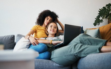 Photo for Lgbtq, laptop and couple relax on sofa for watching movies, streaming series and online videos. Dating, lesbian and happy women on computer for internet, bonding and relationship in living room. - Royalty Free Image