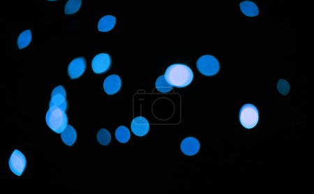 Téléchargez les photos : Bleu, paillettes et bokeh dans un studio avec fond sombre pour la célébration, l'événement ou la fête. Confettis, lumières et étincelles de couleurs pour la magie, brillance ou lueur pour festif par fond noir avec maquette - en image libre de droit