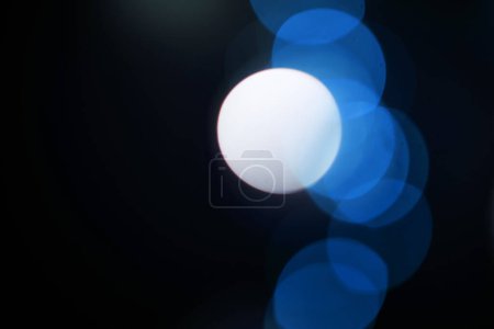 Foto de Bokeh, partículas azules y neón sobre fondo negro con patrón, textura y maqueta con estética cósmica. Iluminación nocturna, luces brillantes y resplandor en el papel pintado oscuro con espacio, brillo de color y destello - Imagen libre de derechos