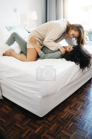 Photo for Happy, playful and a lesbian couple in the bedroom for communication, love and bonding. House, laughing and gay or lgbt women on a bed for conversation, tickle and comfortable in a marriage together. - Royalty Free Image