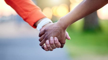Photo for Interracial couple, holding hands and love in nature for support, trust or unity together. Closeup of people touching in romance, care or friendship walk in an outdoor park for partnership or duo. - Royalty Free Image