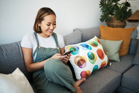 Photo for Woman, phone and happy in living room with relax for social media, communication and technology in home. Person, smile and happiness on sofa with internet, conversation and streaming entertainment. - Royalty Free Image