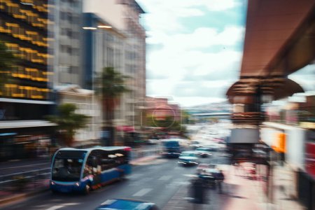Photo for Busy city, road and cars in motion blur for morning traffic, travel and transportation in CBD. Urban commute, office building and street with bus stop, people on sidewalk and fast journey to work - Royalty Free Image