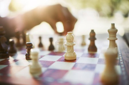 Photo for Closeup, chess and hand at park for challenge, strategy and moving silhouette in sunshine. Person, vintage board game and outdoor for contest, battle and problem solving with competition in summer. - Royalty Free Image