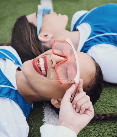 Photo for Friends, sports and laying on field, break and closeup of sunglasses, smile and relax for practice, training and workout. Happy people, playful and lazy for exercise, fashion and accessories for fun. - Royalty Free Image