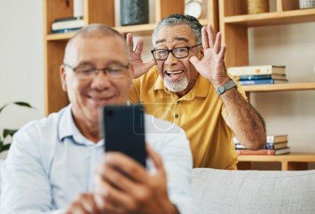 Téléchargez les photos : Drôle, selfie et hommes dans une maison comme amis à la retraite pour se détendre, comédie et internet. Heureux, ensemble et personnes âgées ou âgées avec un téléphone pour un appel photo ou vidéo avec un geste comique. - en image libre de droit