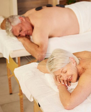 Téléchargez les photos : Pierre chaude, massage du dos et couple de personnes âgées au spa pour un traitement de luxe, d'autosoin et de guérison musculaire. Santé, détente et personnes âgées en retraite pour la thérapie corporelle au salon naturel - en image libre de droit