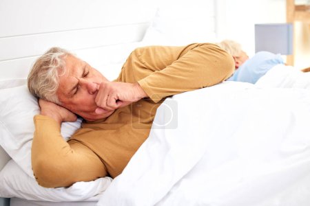 Photo for Couple, coughing or sick old man in bed with wife at home with flu virus, tuberculosis or health problem. Chest pain, mature or senior person with cold fever bug, allergy or lung illness in bedroom. - Royalty Free Image