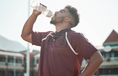Photo for Football player, drink water and rest on sports field for training completion, workout and exercise outdoors. Fitness, workout and male athlete with liquid bottle for wellness, hydration or practice. - Royalty Free Image