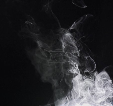 Foto de Humo, niebla o gas en un estudio con fondo oscuro por espacio de maqueta para efecto mágico con abstracto. Niebla de incienso, vapor o vapor que se mueve en el aire para el patrón de niebla de nube por fondo negro con maqueta - Imagen libre de derechos