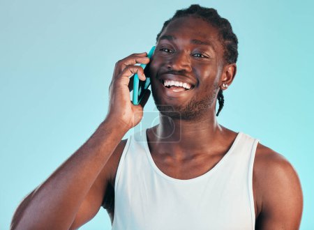 Foto de Llamada telefónica, comunicación y joven negro en el estudio con sonrisa para una conversación feliz. Tecnología, felicidad y modelo masculino africano en discusión móvil con teléfono celular aislado por fondo azul. - Imagen libre de derechos