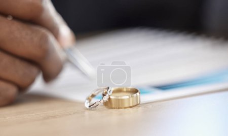 Divorcio, anillos y firma en el papeleo de un abogado, registro de la boda o por escrito en un contrato. Cuadro, primer plano y certificado, planificación o documentación jurídica de un compromiso o compromiso.