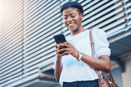 Photo for Cellphone, walking and young woman in the city networking on social media, mobile app or the internet. Happy, technology and African female person scroll on a phone and commuting in urban town street. - Royalty Free Image