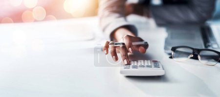 Person, hand and calculator for finance, budget planning or accounting audit on mockup at office. Closeup of accountant or employee in financial management, profit or expenses on bokeh background.