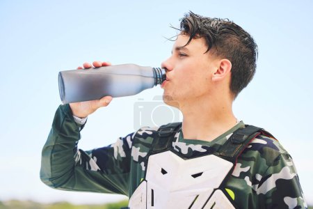 Photo for Man, rider and water for rest after exercise, training or activity on vacation, holiday or travel for competition. Person, racer and break in Namibia for sport, summer and relax with profile in sun. - Royalty Free Image