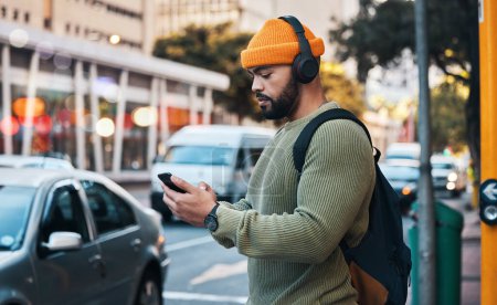 Photo for Phone, headphones of student and man in city listen to music, sound or audio. Smartphone, radio and serious person in street for streaming podcast, typing on social media and reading email to travel. - Royalty Free Image