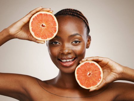 Photo for Woman, grapefruit and portrait of beauty in studio for vitamin c, vegan cosmetics and glow on brown background. Face, happy african model and citrus nutrition for healthy benefits of natural skincare. - Royalty Free Image