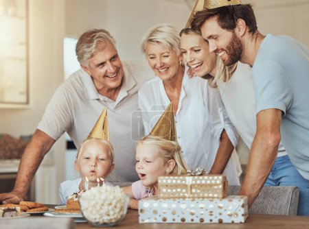 Téléchargez les photos : Parents, grands-parents et enfants à l'anniversaire avec gâteau dans la célébration avec des bonbons, l'amour et le cadeau à la maison. Bonheur, les hommes et les femmes ensemble à la table à la fête des enfants dans la maison avec fille soufflant des bougies. - en image libre de droit