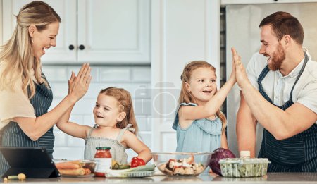 Photo for Happy family in kitchen, cooking with kids and high five with success, learning and nutrition with parents. Mom, dad and girl children making healthy food in home with care, celebration and lunch - Royalty Free Image