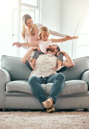 Photo for Parents, kid and airplane on sofa, smile and playful for love, care or bonding in living room at family home. Father, mother and daughter with plane game, excited or together on lounge couch in house. - Royalty Free Image
