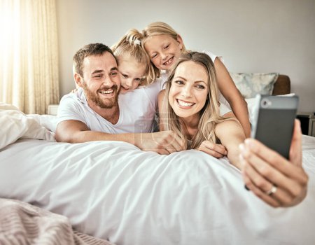 Téléchargez les photos : Selfie, heureux et portrait de famille sur le lit pour coller et se détendre ensemble à la maison moderne. Sourire, amour et fille enfants pondre et prendre une photo avec des parents de l'Australie dans la chambre - en image libre de droit