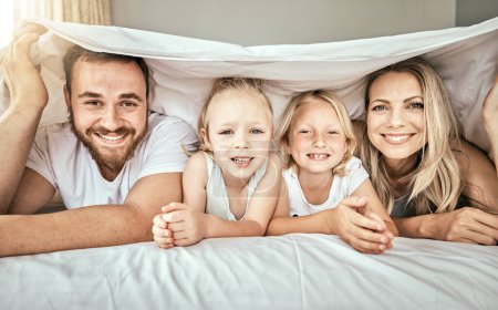 Téléchargez les photos : Heureux, sourire et portrait de famille sur le lit avec couverture pour coller et se détendre ensemble à la maison. Bonheur, amour et fille enfants couchant avec des parents d'Australie dans la chambre à coucher à la maison moderne - en image libre de droit