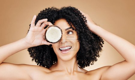 Photo for Beauty studio face, happy woman and coconut for skin detox, natural wellness treatment or facial makeup. Happiness, fruit benefits and aesthetic person with food skincare product on brown background. - Royalty Free Image