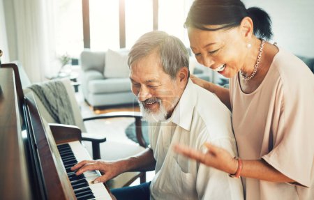 Téléchargez les photos : Couple de personnes âgées jouant du piano pour la musique dans le salon pour se lier, se divertir ou s'amuser. Heureux, sourire et vieux asiatique homme et femme à la retraite profiter instrument à clavier à la maison moderne - en image libre de droit