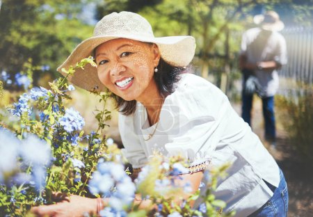 Photo for Portrait, mature and woman for gardening with hat, landscaping and backyard in spring. Asian person, grandmother and love with smile for blue flowers in bloom for peace, relax or wellness for care. - Royalty Free Image