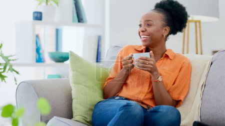 Photo for Black woman, house and couch with coffee, relaxing and smiling for self care, living room and break. Me time, comfort and quality time in home, sofa and day off for resting, laughing and happiness. - Royalty Free Image