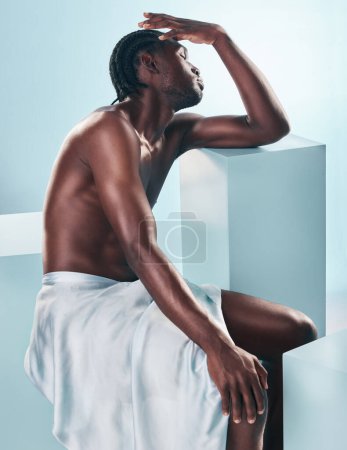 Photo for Body, black man and beauty of art and thinking profile in studio with skincare and glow from wellness and towel. Strong muscle and African model with creative blue background and relax with fitness. - Royalty Free Image