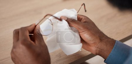 Téléchargez les photos : Mains, lunettes et chiffon pour le nettoyage, le gros plan et l'entretien de la lentille, du cadre et de la santé oculaire à la maison. Personne, tissu et lunettes pour l'optométrie, vision claire et bien-être pour la vue à table. - en image libre de droit