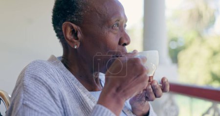 Photo for Senior woman, thinking and relax with coffee on a front porch with nostalgia at a nursing home. Assisted living, tea and elderly African female enjoy a calm drink, peace or fresh air alone outdoors. - Royalty Free Image