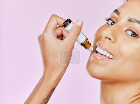 Photo for Face, care for lips and skincare with woman and beauty in studio, liquid collagen or serum on pink background. Portrait, smile and product for mouth, dermatology with oil and cosmetics or gloss. - Royalty Free Image