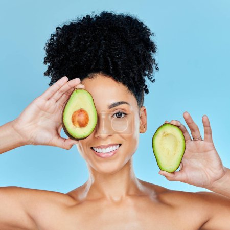 Photo for Happy woman, portrait and avocado for skincare, diet or natural beauty against a blue studio background. Face of female person smile with organic fruit for nutrition, vitamin C or skin wellness. - Royalty Free Image