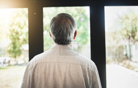 Photo for Back, mature man and thinking by window, depression and anxiety alone in home. Rear view, retirement and sad person contemplating in house, planning future and remember memory, idea or reflection. - Royalty Free Image