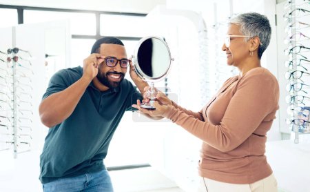Photo for Mirror, glasses and optometrist help happy man in store for choice of lens, frame and consultation. Smile, reflection and mature optician with patient for spectacles, healthy vision and ophthalmology. - Royalty Free Image