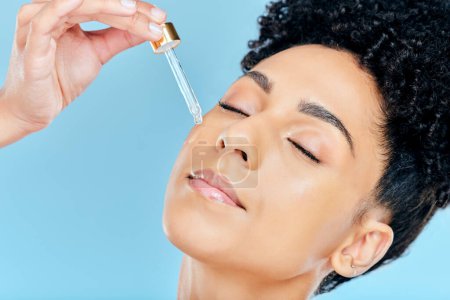 Photo for Beauty, relax face and woman with serum application for skin hydration, anti aging and collagen essential oil liquid for skincare. Retinol dropper, hyaluronic acid or studio person on blue background. - Royalty Free Image