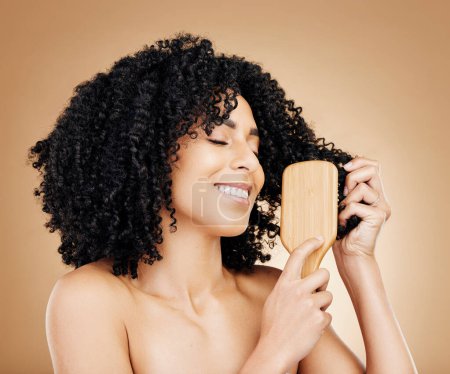 Téléchargez les photos : Afro, cheveux et brosse de femme en studio avec sourire, croissance naturelle et texture saine de bobine sur fond brun. Outils de coiffure, coiffure bouclée et peigne pour l'esthétique de salon, kératine et cosmétiques de beauté. - en image libre de droit
