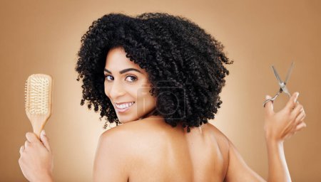 Photo for Hair care, portrait and a woman with a brush and scissors for grooming, styling or beauty. Smile, hairdresser and a young girl with an afro and tools for a hairstyle or cut on a studio background. - Royalty Free Image
