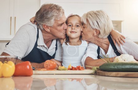 Photo for Family, cooking and grandparents kiss girl child in kitchen with love, care and support at home. Food, learning and face of kid with elderly people together with vegetables, nutrition or prepare meal. - Royalty Free Image