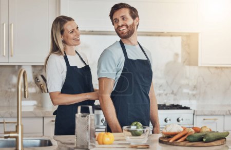 Photo for Kitchen, apron and couple with cooking, smile and healthy food with ingredients, bonding and anniversary. Happy people, home and man with woman, recipe and bonding with activity, lunch and vegetables. - Royalty Free Image