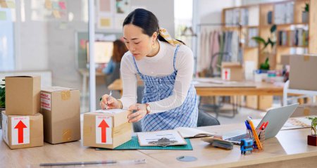 Photo for Ecommerce, Asian woman with checklist and boxes at laptop, reading sales or inventory at fashion startup. Online shopping, delivery and small business owner, stock list for web shop package checking - Royalty Free Image