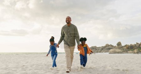 Téléchargez les photos : Randonnée pédestre, père et enfants se tenant la main à la plage pour nouer des liens, liberté estivale et soins. Heureux, la famille et un père africain avec affection pour les enfants lors d'une promenade dans le sable à l'océan en vacances. - en image libre de droit