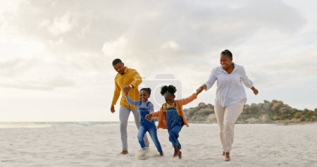 Téléchargez les photos : Heureux, voyager et se tenir la main avec la famille noire à la plage pour l'été, les vacances et se détendre. Vacances, soutien et amour avec les parents et les enfants marchant sur le littoral pour les soins, la confiance et la liberté. - en image libre de droit